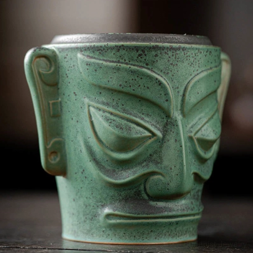 Close-up side-front view of ceramic incense burner showing detailed carved facial features and speckled green finish with fitted lid