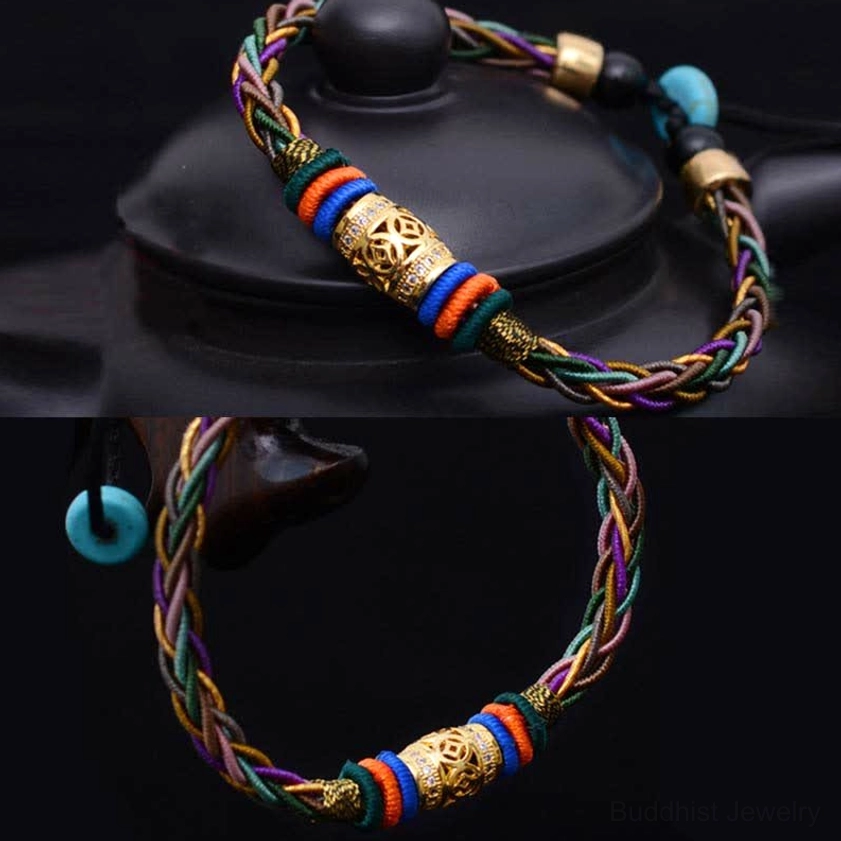 Two matching handmade Buddhist red string bracelets with copper coin charms on black teapot, showcasing multicolor braided rope and gold metal accents
