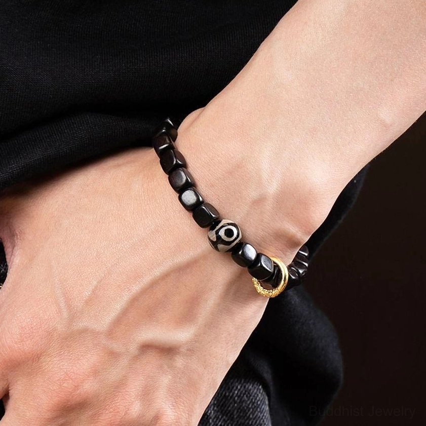 Two matching ebony wood dzi bracelets worn on wrists together, showing cubic dark wood beads with dzi bead and gold accent ring for couples or dual wearing