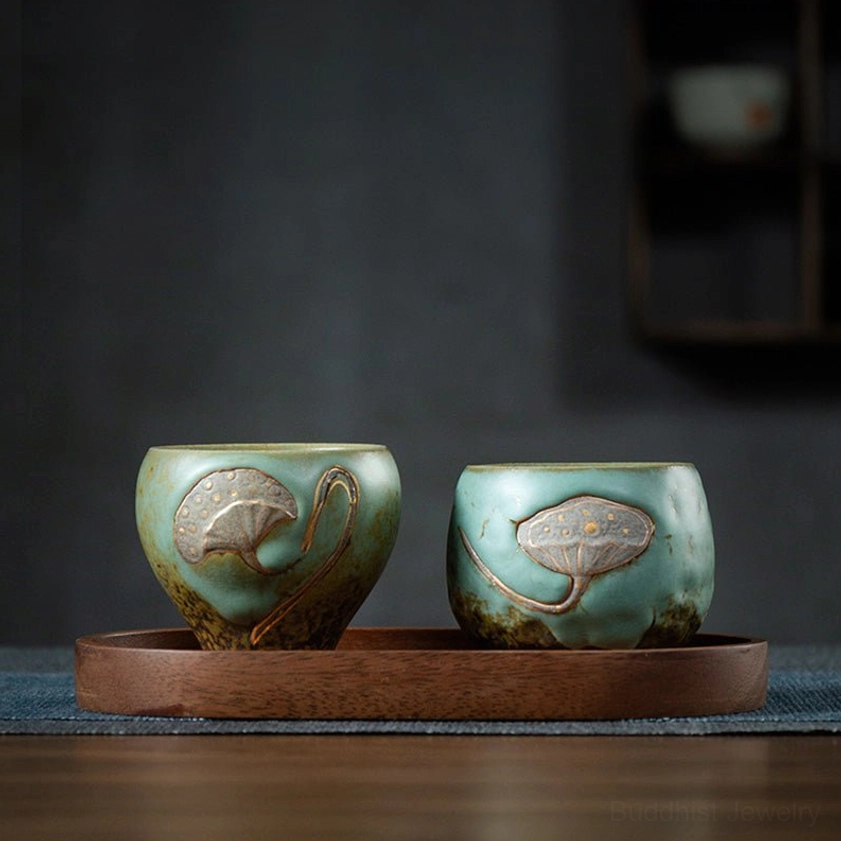 Pair of turquoise glazed lotus engraved ceramic tea cups on wooden tray, oblique tabletop display
