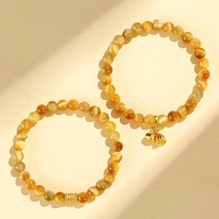 Two matching tiger eye buddhist bracelets with gold leaf pendants flat lay