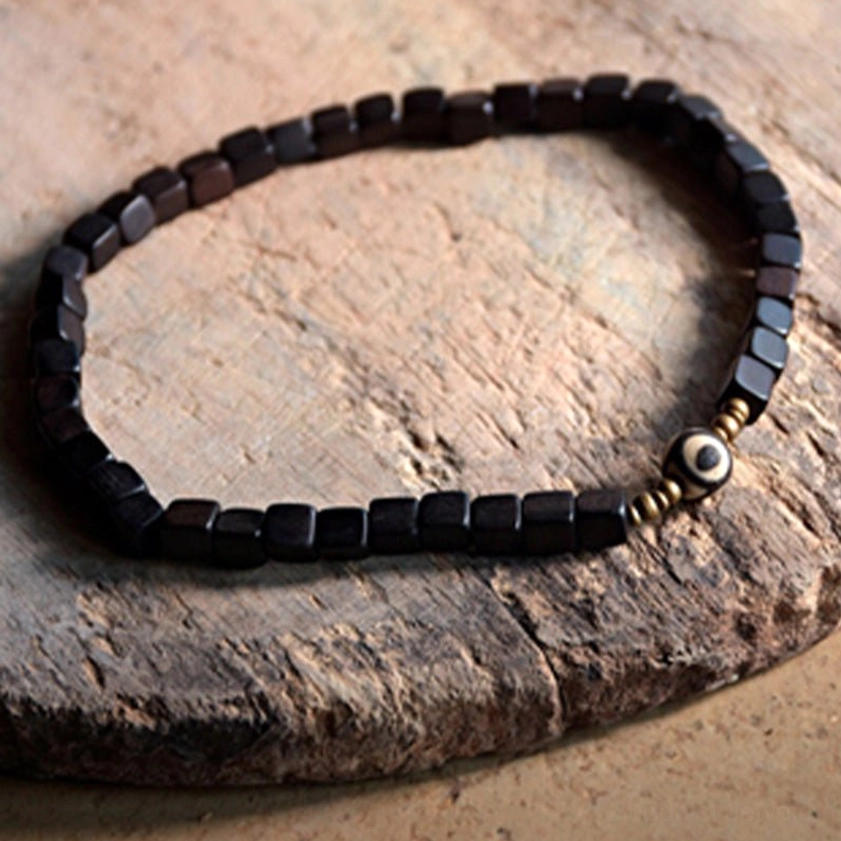 Matte black square ebony wood bracelet with small gold spacers and single eye dzi charm