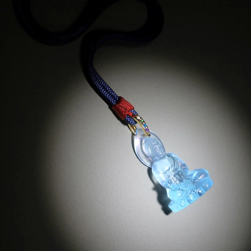 Medicine Buddha pendant on blue lanyard with red knot and gold attachment bail spotlight view