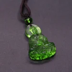 Handcrafted Liuli crystal green Medicine Buddha pendant necklace with halo, close-up front view showing translucent emerald glass seated Buddha figurine