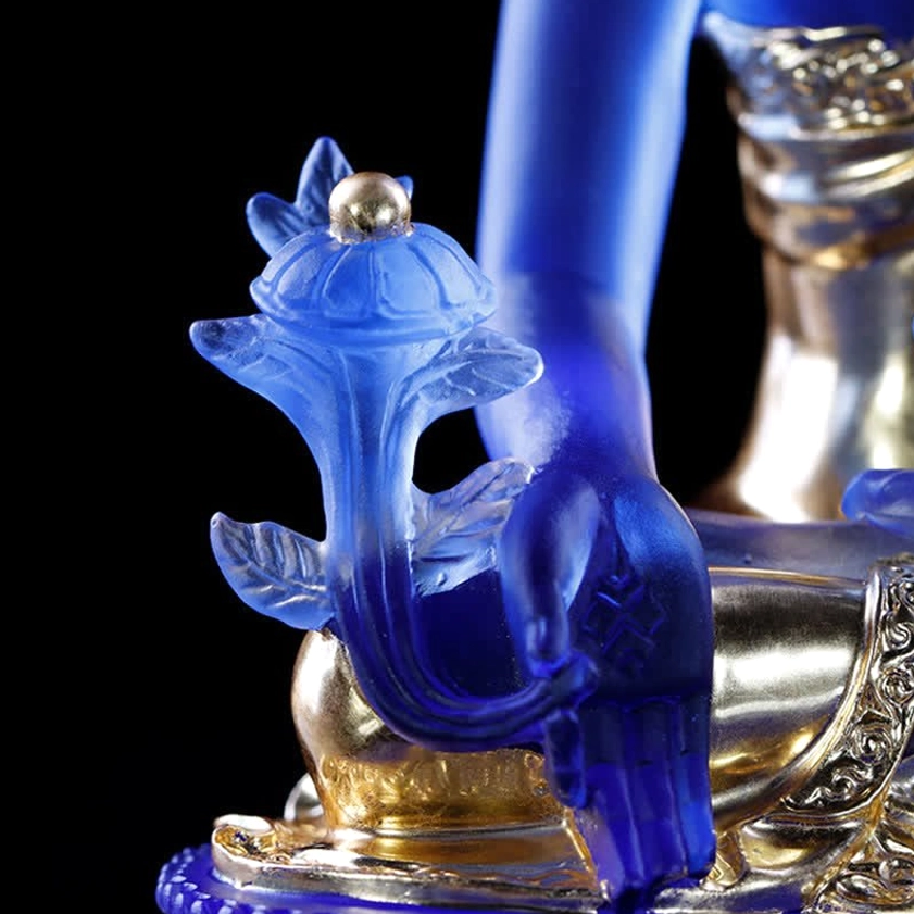 Medicine Buddha crystal glass statue left-front diagonal angle view with green plant ornaments, deep blue body, gilded details