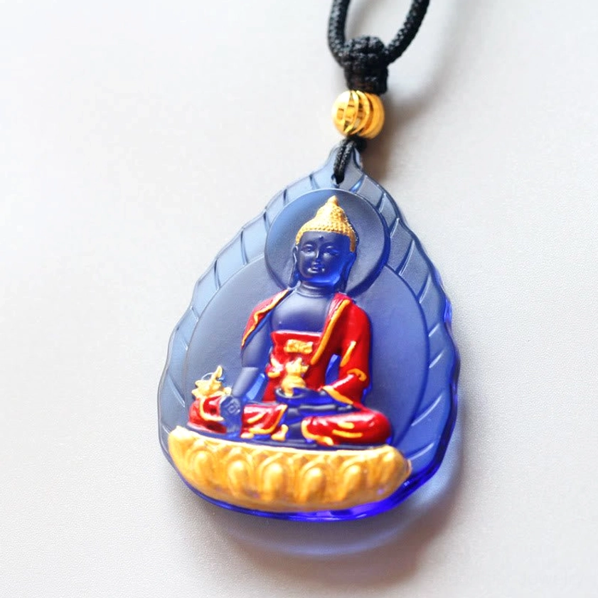 Leaf-frame Medicine Buddha Liuli pendant with deep blue glass and gilded Buddha figure on black cord with gold bead