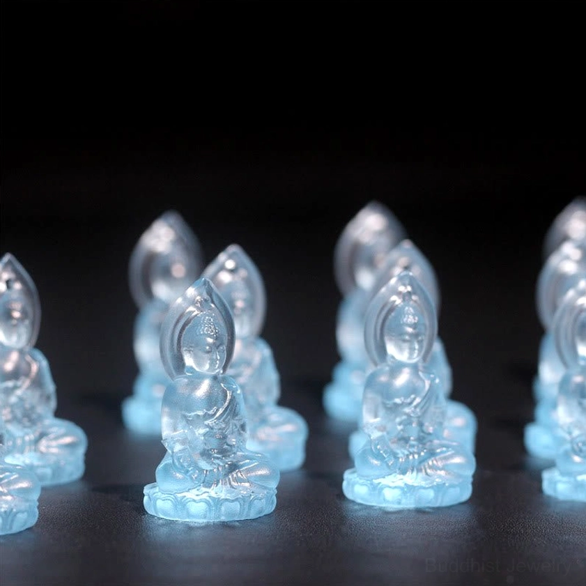 Multiple blue Medicine Buddha Liuli crystal pendants flat lay showing uniform translucent design and seated lotus style