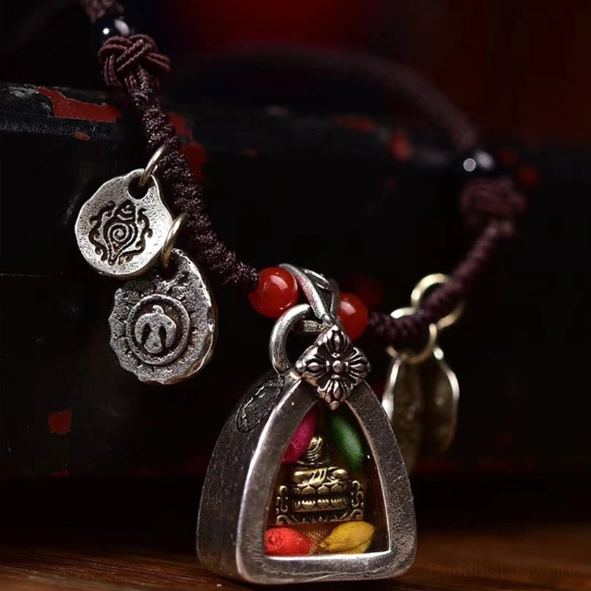 Three-quarter front view of Medicine Buddha braided rope necklace with enclosed Buddha statue and colored fillers on dark wood