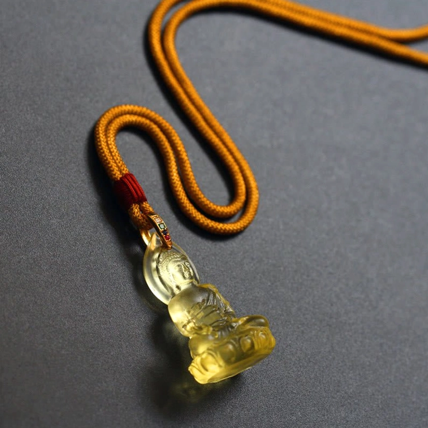Medicine Buddha pendant detail showing intricate carved features and translucent blue Liuli crystal quality