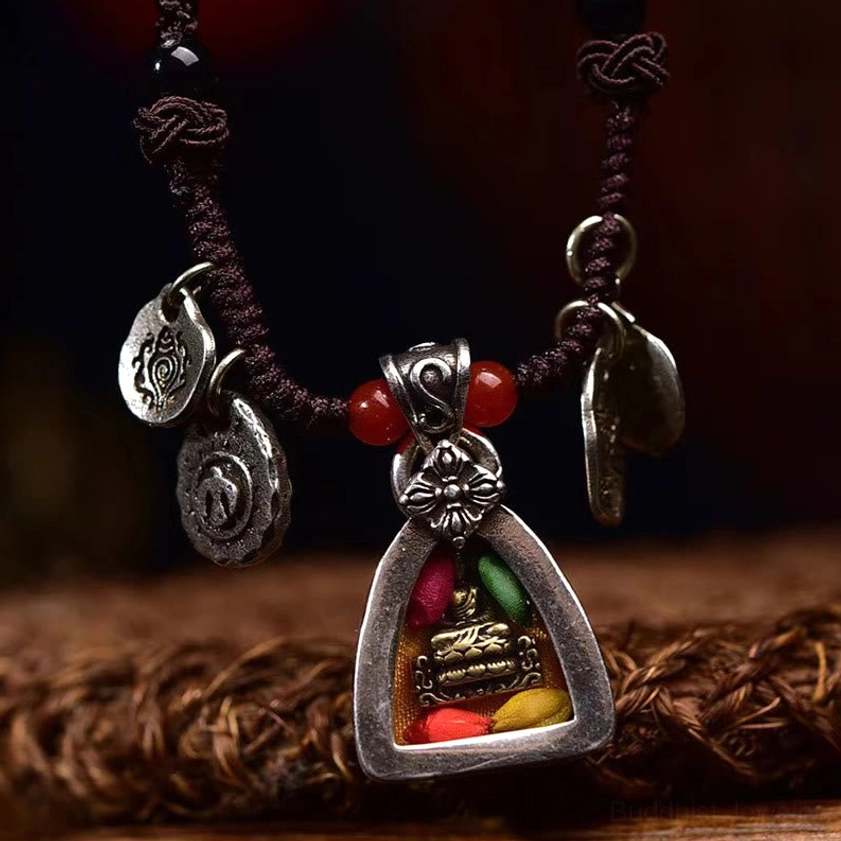 Close-up front view of Medicine Buddha pendant necklace showing triangular silver frame with colored decorative details