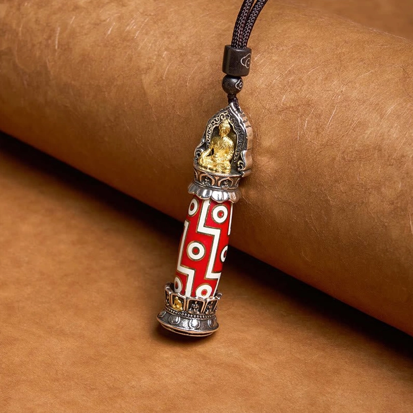 Medicine Buddha Nine-Eye Dzi pendant with red-white geometric patterns and gold Buddha shrine ornament on braided cord