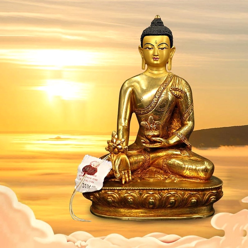 Medicine Buddha gilt bronze statue in cross-legged meditation pose with lotus pedestal against warm sunset backdrop