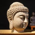Meditating Buddha head resin statue three-quarter side view showing closed eyes and serene facial expression on wooden display shelf