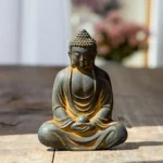 Meditating Buddha statue with cross-legged meditation pose, dark grey iron powder resin with rustic gold accents, held in hands detail