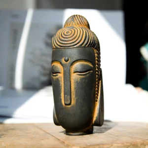 Meditating Buddha statue with closed eyes and rust patina finish on wooden desk with open books