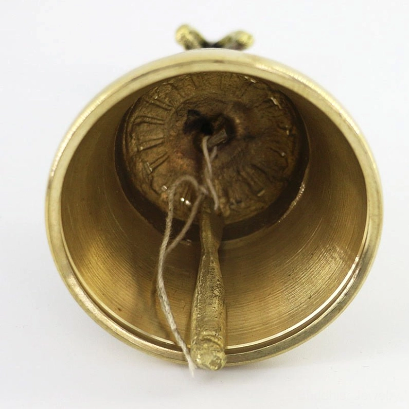 Internal view of meditation bell showing polished brass interior, attached clapper with twine, and engraved clapper patterns