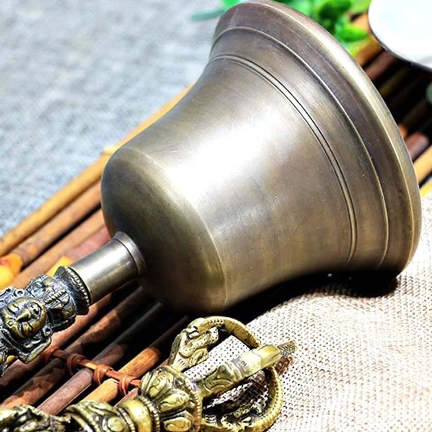 Meditation bell with brushed matte bronze surface texture, low angle view on natural linen and bamboo