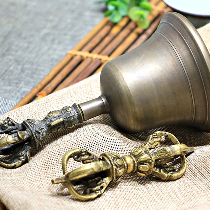 Meditation bell with ornate carved handle detail on natural backdrop, showcasing traditional Buddhist ritual instrument artistry