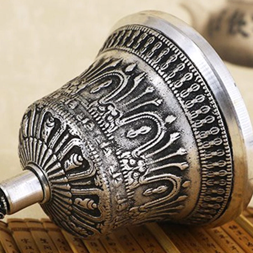 Side close-up view of Buddhist meditation bell showing radial and floral relief carvings with aged silver finish