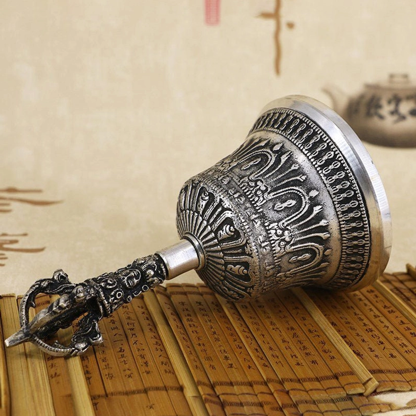 Tibetan meditation bell with decorated handle laid down side profile showing full carved religious patterns