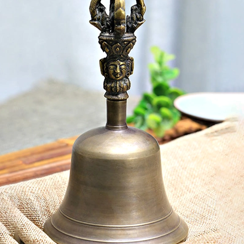 Meditation bell side view with decorative Buddha handle on natural bamboo mat and linen background