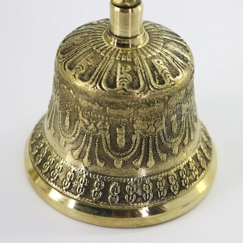 Close-up detail of meditation bell top section showing embossed religious decorative patterns and polished copper brass finish