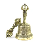 Handmade copper meditation bell and vajra dorje ritual set with antique brass finish and intricate carved details, shown in flat lay display view