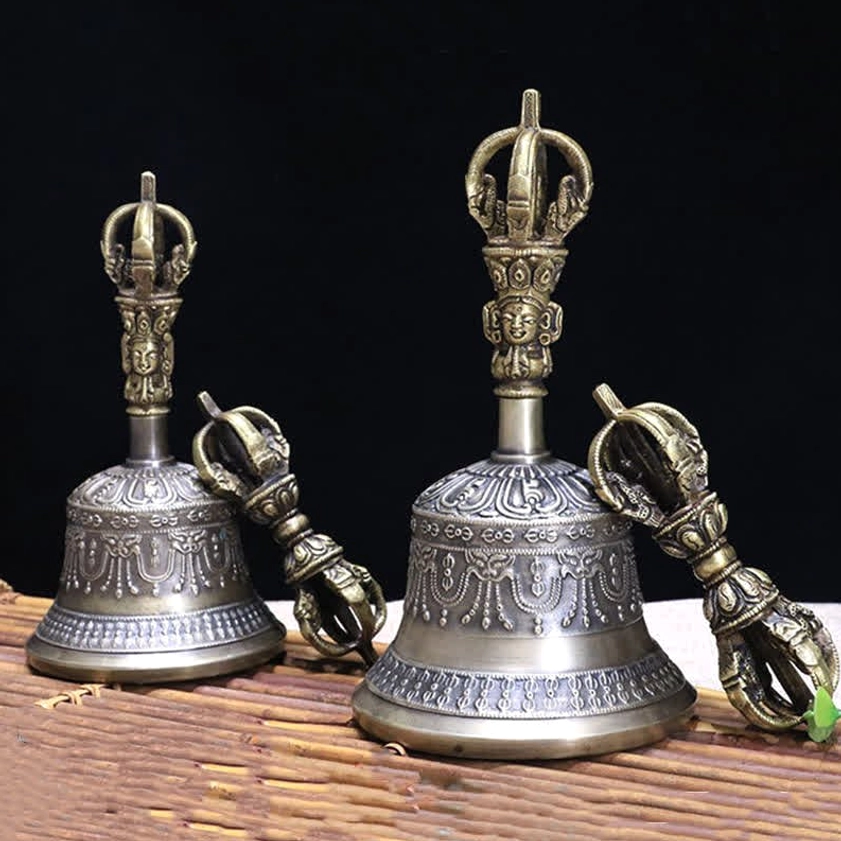 Two handcrafted copper meditation bells with matching vajra dorjes displaying dual-tone finish on bamboo mat with black backdrop