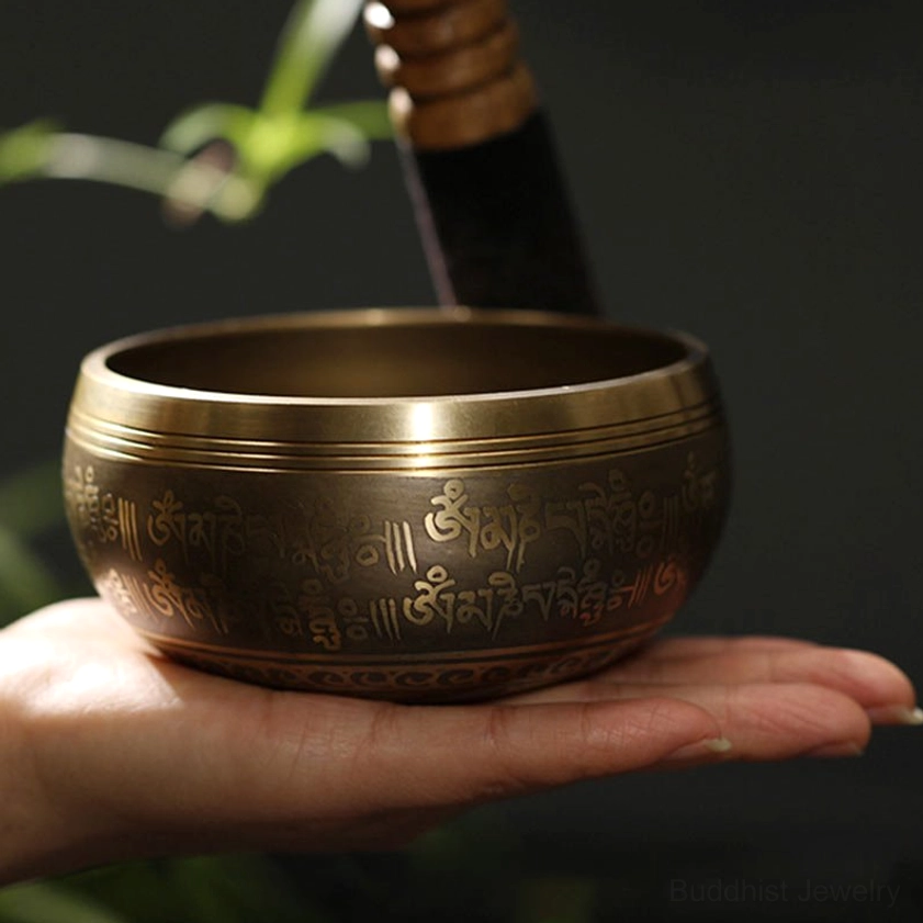 Buddhist singing bowl with engraved sacred script shown in human palm demonstrating portable size