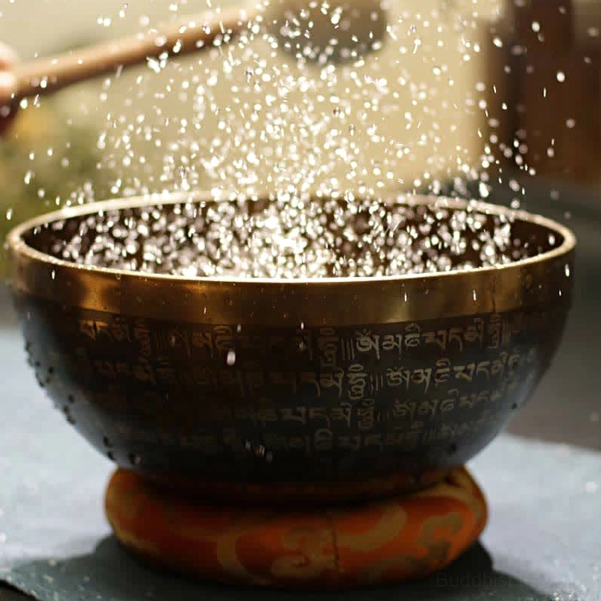 Buddhist singing bowl on red cushion demonstrating water vibration resonance effect when struck