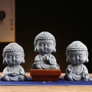 Set of 3 handcrafted meditation Buddha statues in grey sandstone with varied sacred postures displayed on wooden tea table