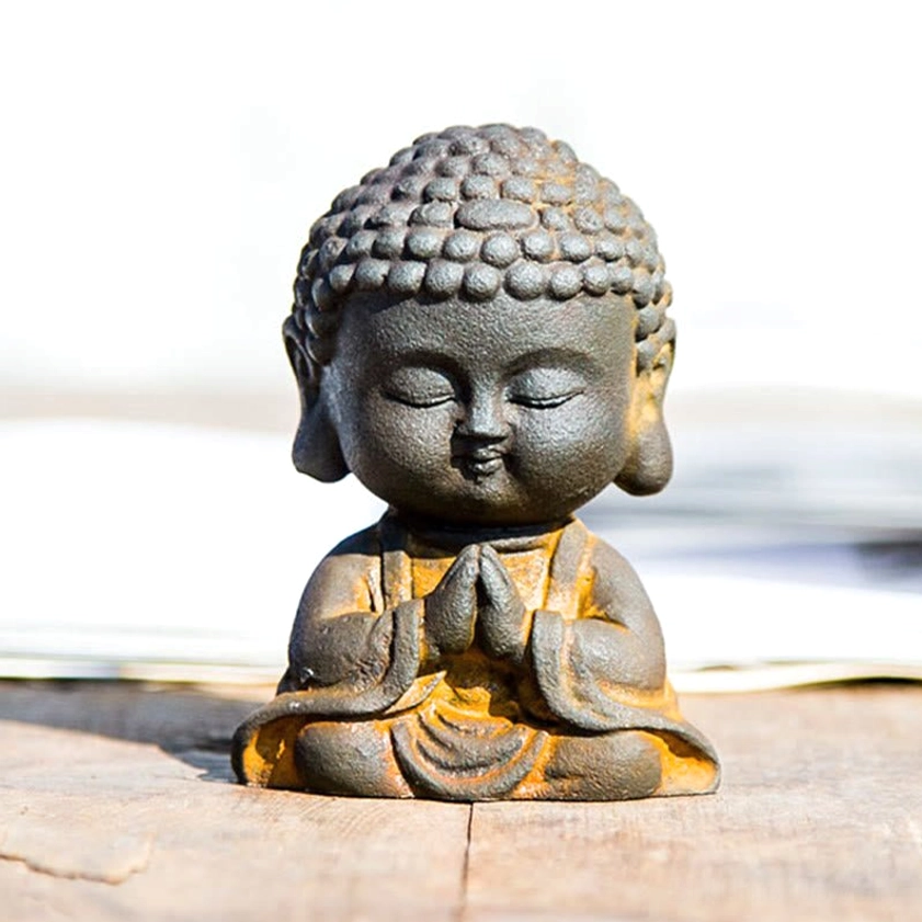 Sunlit view of meditation Buddha statue on wooden surface highlighting rustic weathered finish and yellow robe accents