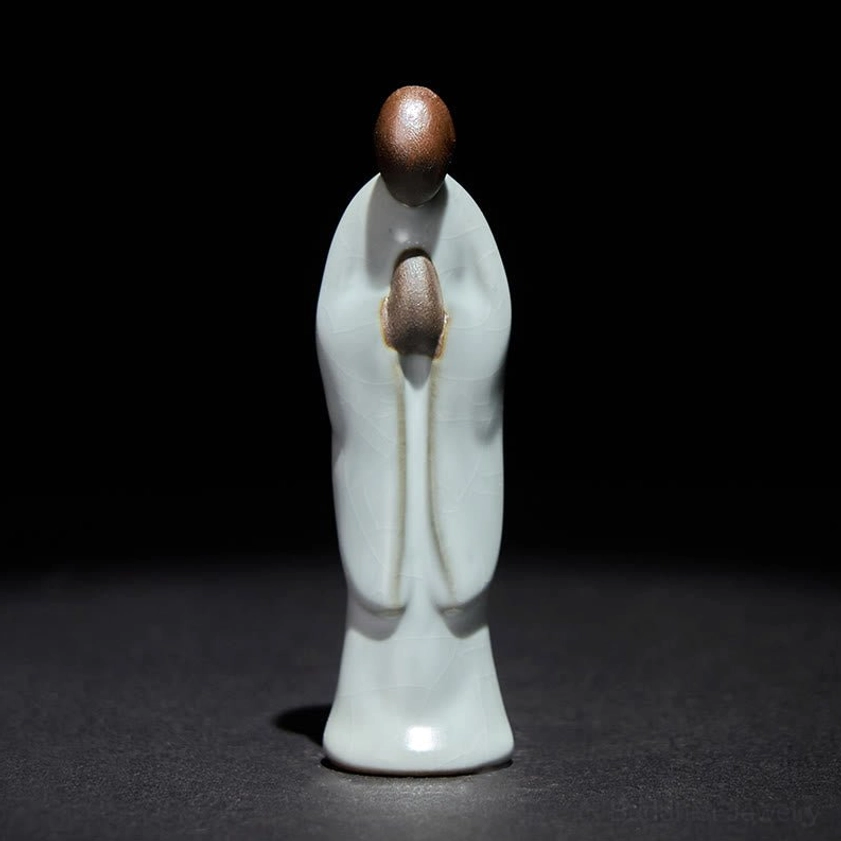 Ceramic Buddhist monk figurine in serene pose, direct front facing view with clasped hands