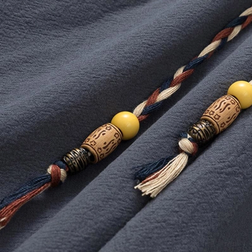 Detail of Buddhist meditation pants drawstring - handcrafted cord with wooden bead accents and tassel, showing traditional ethnic decoration reflecting Buddhist craftsmanship