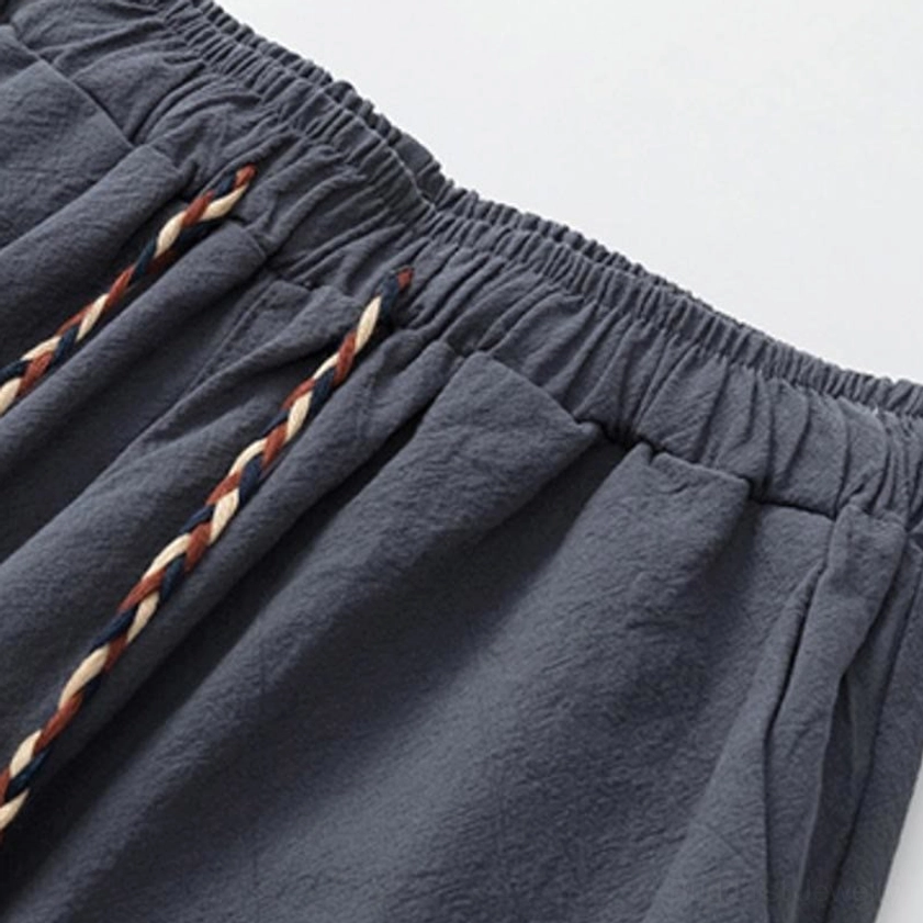 Close-up detail of meditation pants waist - dark gray elastic waistband with decorative woven ethnic-style drawstring showing traditional Buddhist design elements