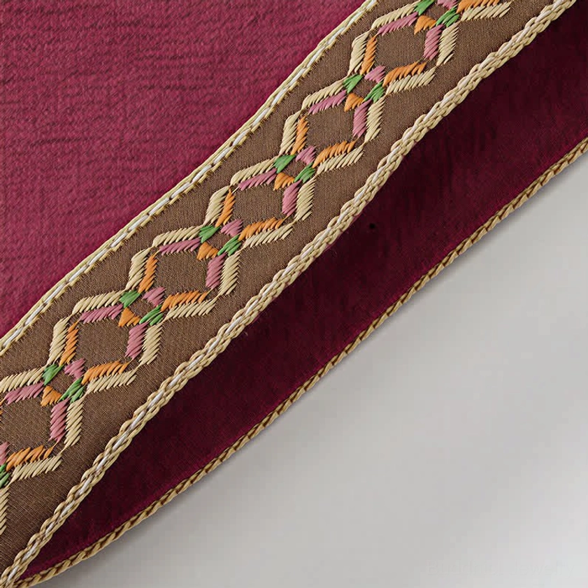 Geometric embroidered trim with colorful stitching and gold border on meditation shirt cuff