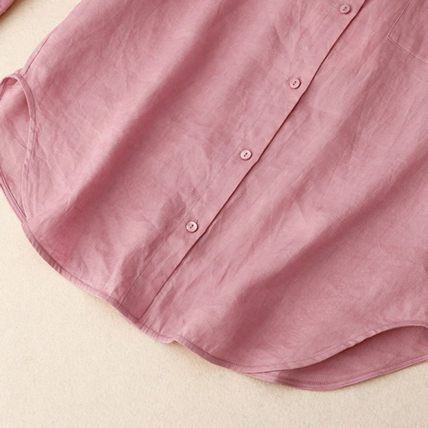 Close-up flat view of meditation shirt front hem and button closure on breathable lightweight fabric