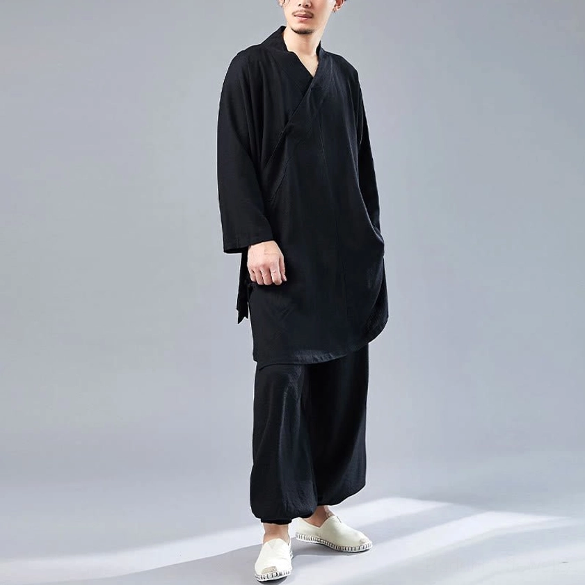 Full-body view of man wearing black Tai Chi meditation uniform in studio setting