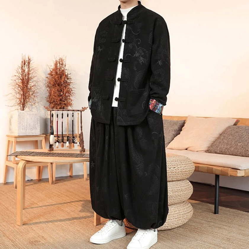 Three-quarter angle of black dragon Tang suit, one hand in jacket pocket, colorful embroidered cuff details