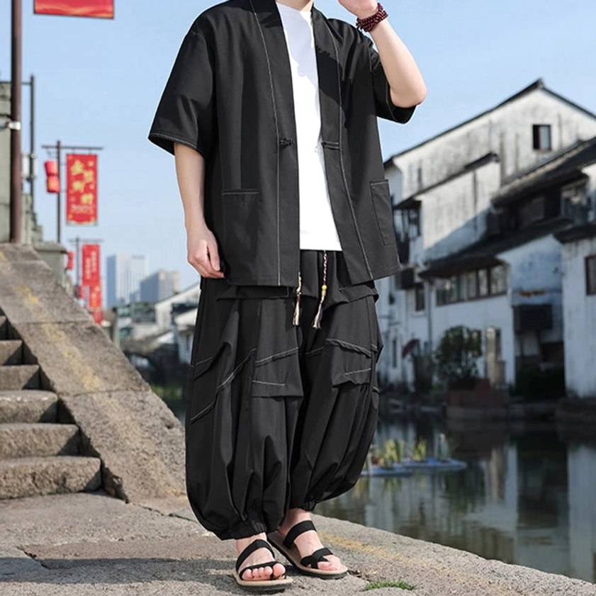 Black meditation kimono set with drawstring waist pants and hands raised near shoulders, showcasing relaxed fit
