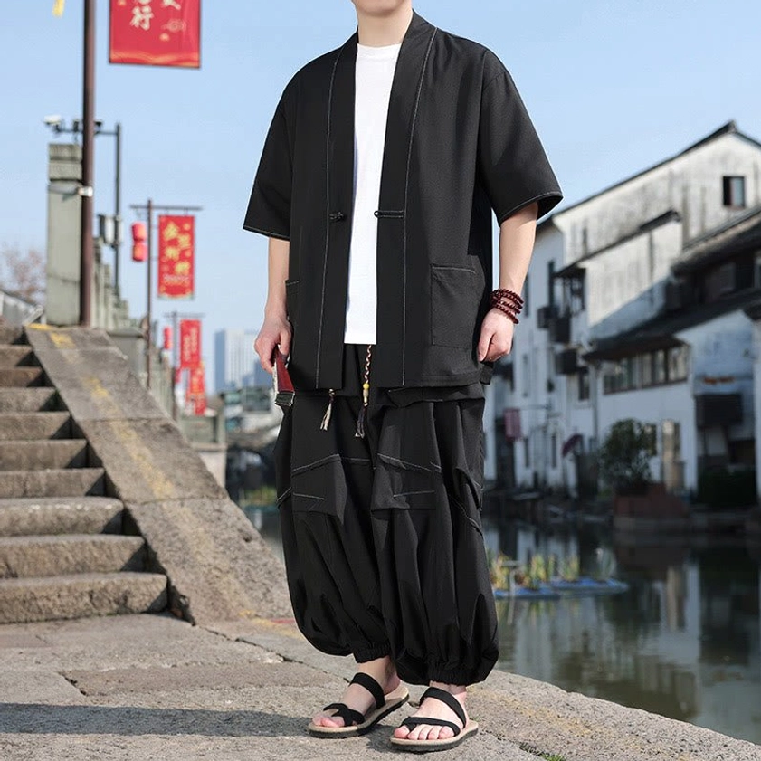Black kimono two-piece outfit worn with relaxed standing pose and small red accessory held in hand