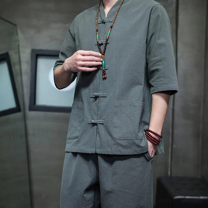 Men's Buddhist meditation cotton linen tang suit top upper-body close-up showing frog buttons, chest pockets, and beaded necklace