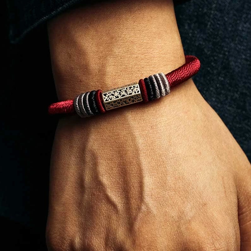Male model wearing red Buddhist string bracelet with polished silver hardware and intricate engraving