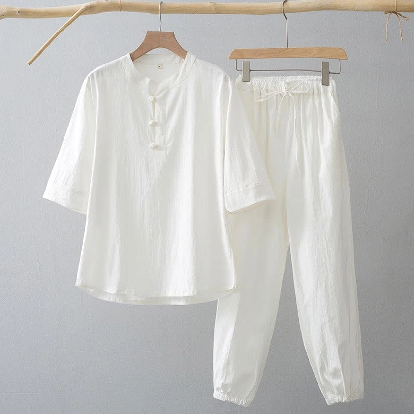 Pure white men's meditation shirt and pants set with Chinese frog buttons, three-quarter sleeves, and drawstring waist, studio product display