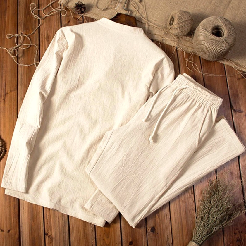 Back view of men's beige cotton-linen two-piece set showcasing rear design and drape on rustic wooden surface