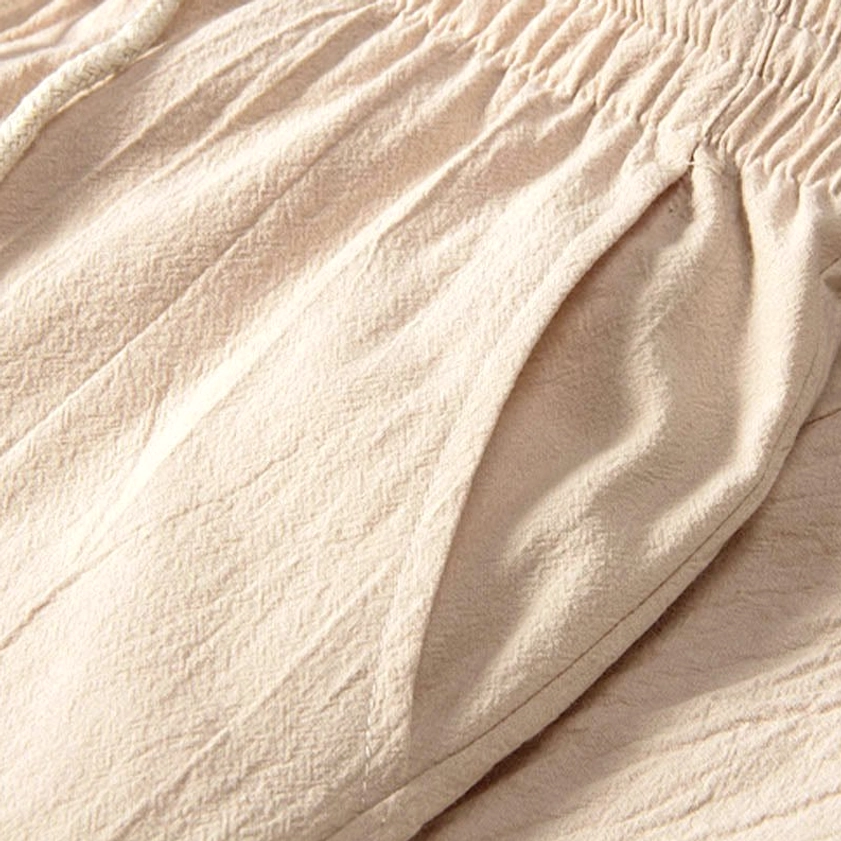 Close-up detail of beige crinkled cotton-linen fabric texture and seam stitching for meditation clothing set