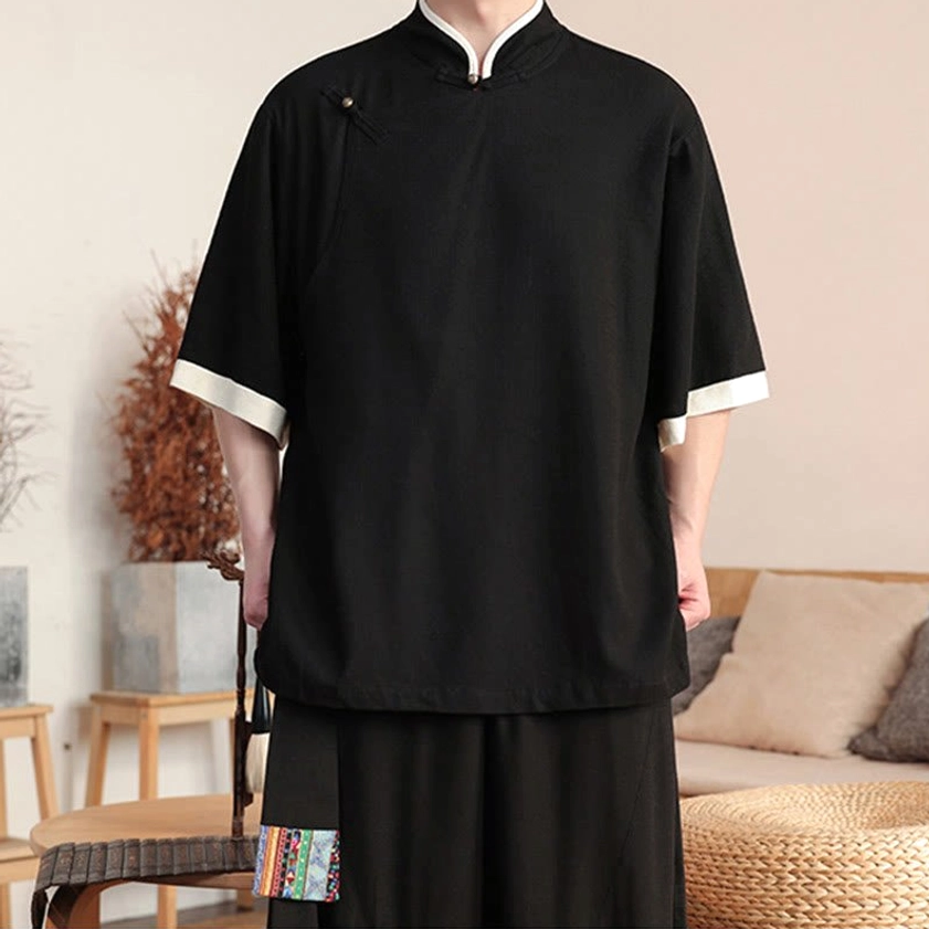 Close-up front view of black Buddhist meditation suit with frog button stand collar and white sleeve trim