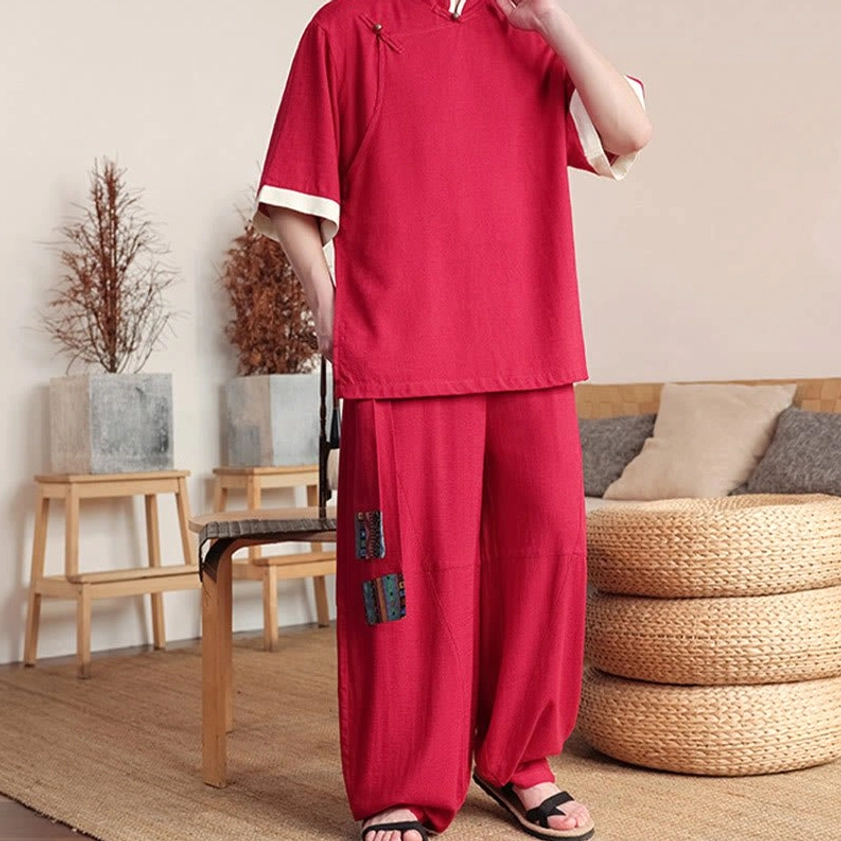 Three-quarter front view of red Buddhist meditation suit with hand adjusting traditional frog button collar