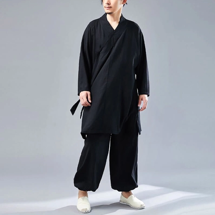 Three-quarter view of black meditation uniform showing asymmetrical collar design