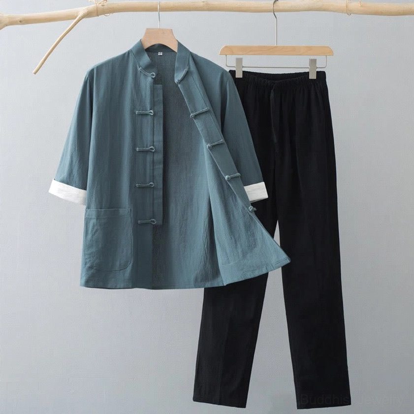 Men's Tang suit two-piece set with teal green top and black pants displayed on wooden hanger, featuring traditional frog button closure and white contrast cuffs